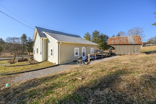 rear view of property with a yard and an outdoor structure