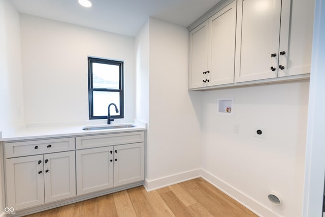 washroom featuring hookup for an electric dryer, light wood-type flooring, hookup for a washing machine, cabinets, and sink