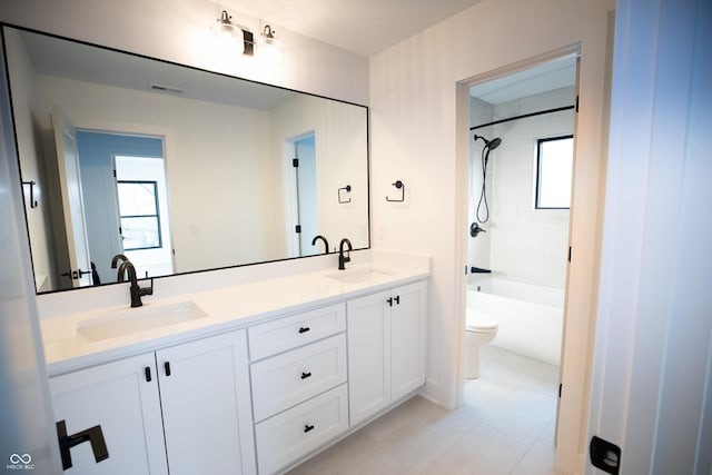 full bathroom featuring toilet, a healthy amount of sunlight, tiled shower / bath, and vanity