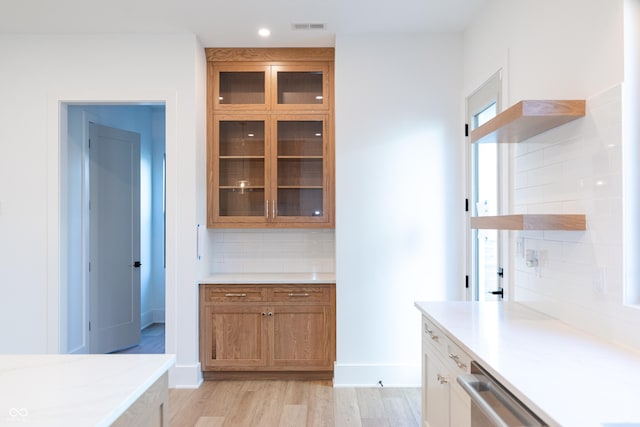 kitchen with light wood-type flooring, decorative backsplash, and dishwasher