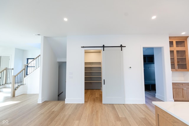 interior space featuring a spacious closet, a closet, light wood-type flooring, ensuite bathroom, and a barn door