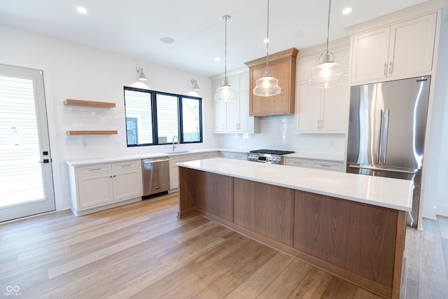 kitchen with appliances with stainless steel finishes, decorative backsplash, a center island, hanging light fixtures, and sink