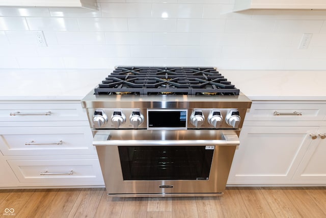 details featuring white cabinets, light stone countertops, stainless steel range with gas stovetop, and light hardwood / wood-style flooring