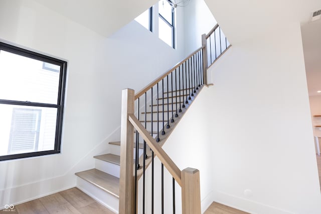 stairs with plenty of natural light and hardwood / wood-style floors