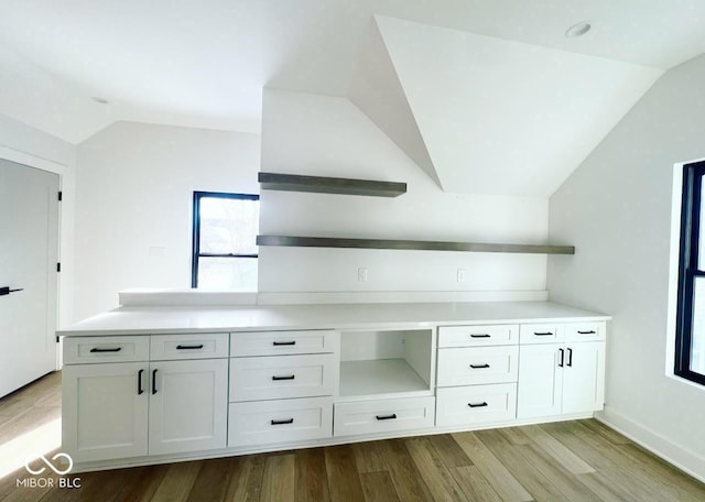 kitchen with light wood-type flooring, white cabinetry, and vaulted ceiling