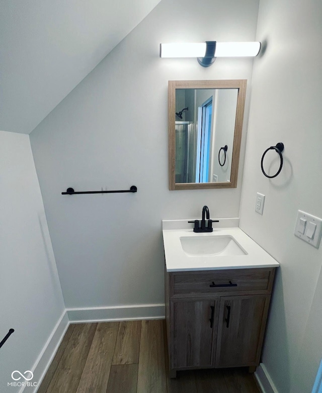 bathroom featuring hardwood / wood-style floors, vanity, and vaulted ceiling