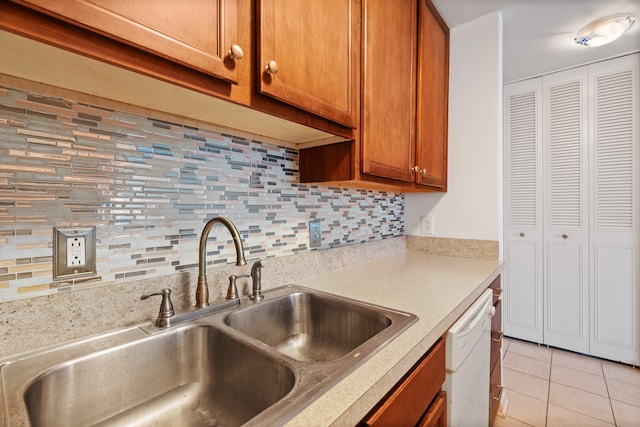 kitchen featuring white dishwasher, tasteful backsplash, sink, and light tile flooring