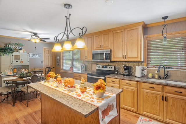 kitchen with ceiling fan, light hardwood / wood-style floors, sink, stainless steel appliances, and a center island