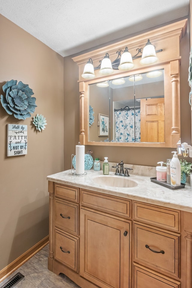 bathroom with a textured ceiling, large vanity, and tile floors