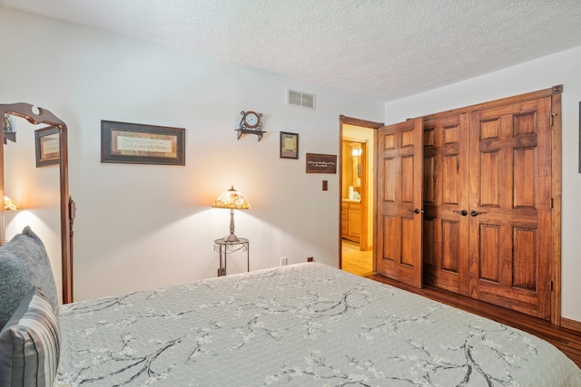 bedroom with a textured ceiling, light wood-type flooring, and a closet