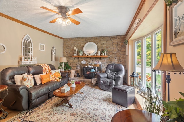 living room featuring ceiling fan, light hardwood / wood-style flooring, a stone fireplace, and a textured ceiling