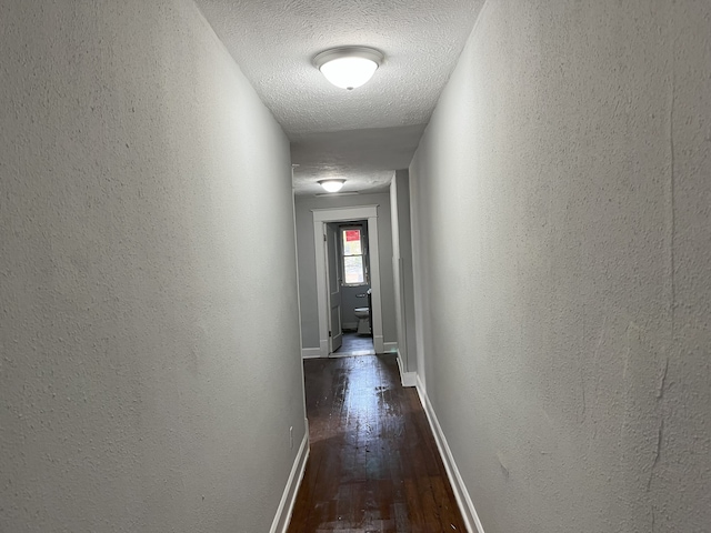 corridor featuring dark hardwood / wood-style flooring and a textured ceiling