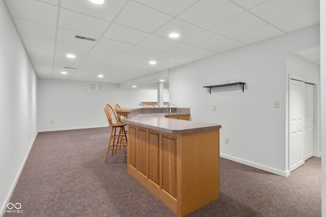 bar featuring dark carpet and a drop ceiling