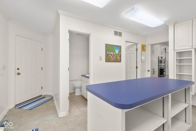 kitchen featuring white cabinetry, light tile patterned floors, crown molding, and double oven