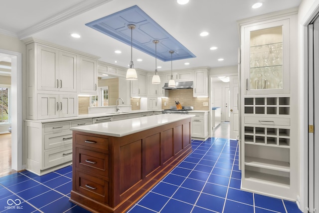 kitchen featuring sink, dark tile patterned floors, a center island, white cabinets, and decorative light fixtures