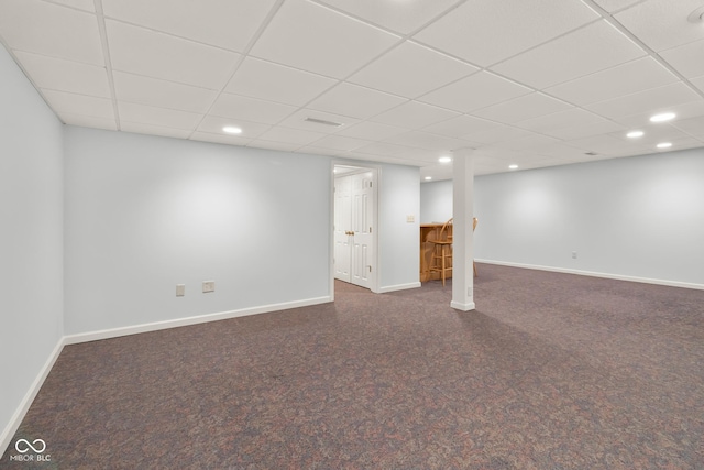 basement featuring a paneled ceiling and dark colored carpet