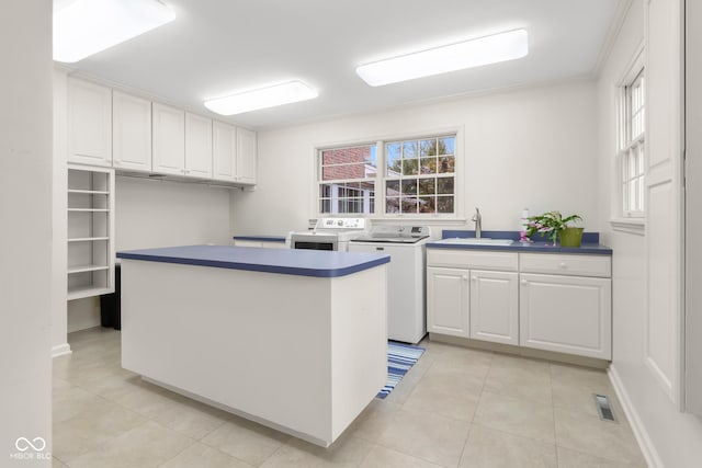 kitchen with white cabinetry, plenty of natural light, washer and dryer, and sink