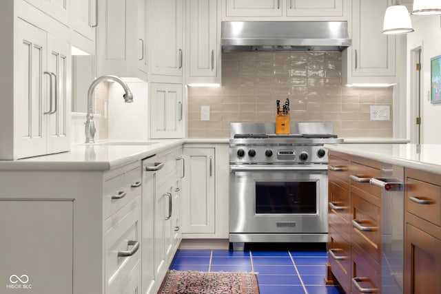 kitchen with sink, stainless steel stove, range hood, white cabinets, and decorative light fixtures