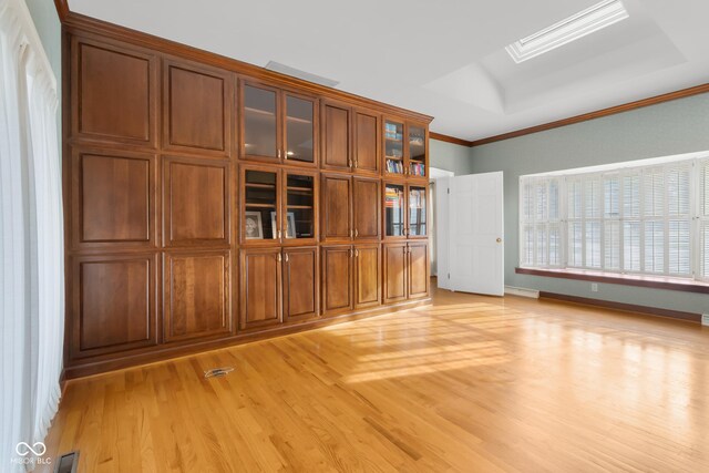 unfurnished living room featuring crown molding, light hardwood / wood-style flooring, and a raised ceiling