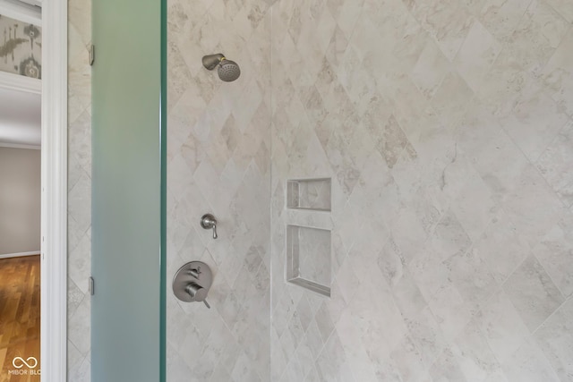 bathroom featuring tiled shower and ornamental molding