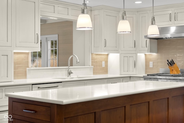 kitchen with pendant lighting, dishwasher, sink, white cabinets, and decorative backsplash