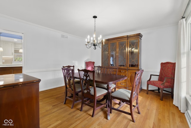 dining room featuring a baseboard heating unit, crown molding, a chandelier, and light wood-type flooring