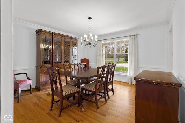 dining area with ornamental molding, light hardwood / wood-style flooring, and a notable chandelier