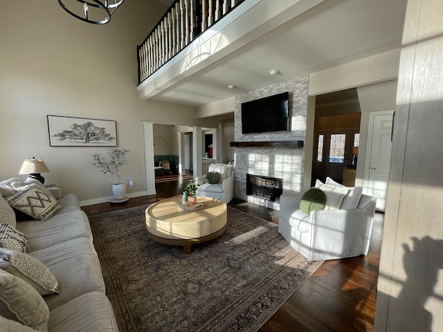 living room with wood-type flooring, a high ceiling, and a fireplace