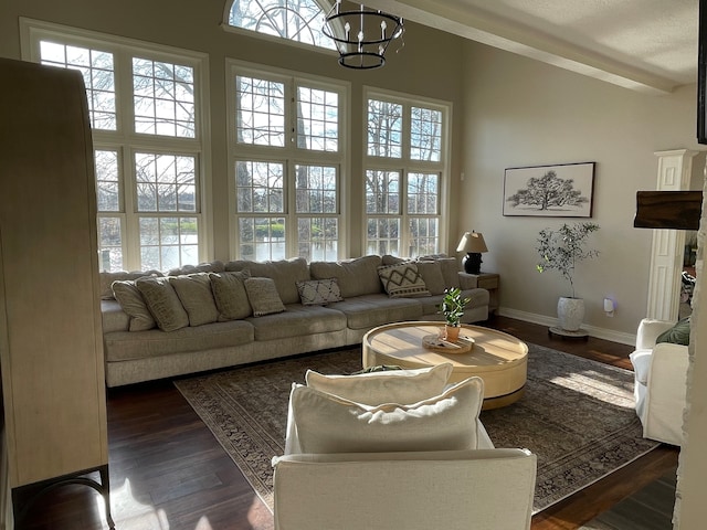 living room with a wealth of natural light, beamed ceiling, dark hardwood / wood-style floors, and a chandelier