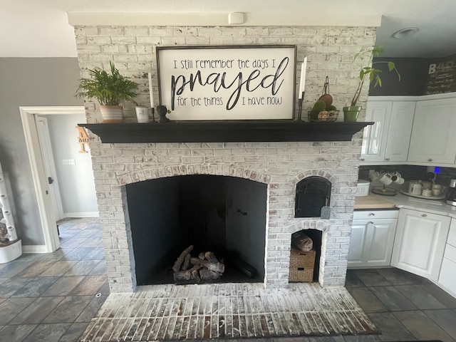 details with dark tile floors and a brick fireplace