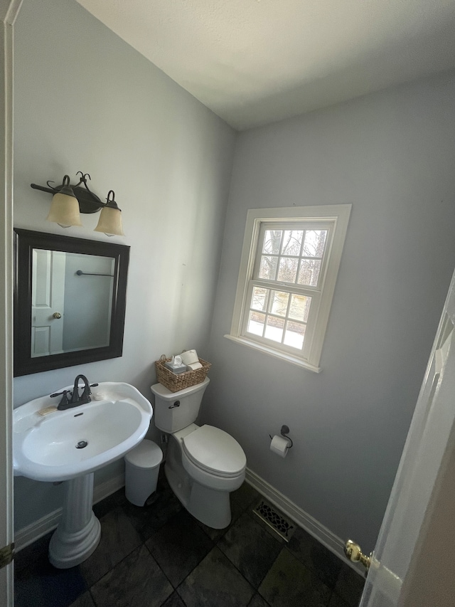 bathroom with toilet, tile flooring, and sink