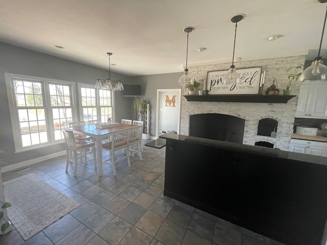 kitchen featuring pendant lighting, white cabinets, tile floors, a chandelier, and a stone fireplace