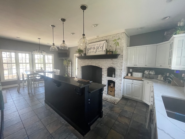 kitchen featuring dark tile floors, tasteful backsplash, white cabinetry, and a brick fireplace