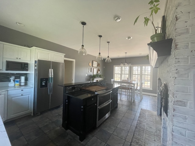 kitchen with decorative light fixtures, stainless steel fridge, white cabinetry, black microwave, and dark tile floors