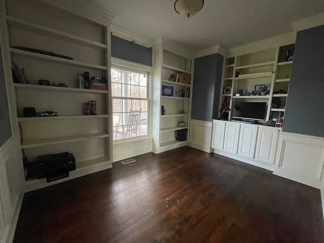 empty room with dark hardwood / wood-style flooring, crown molding, and built in shelves