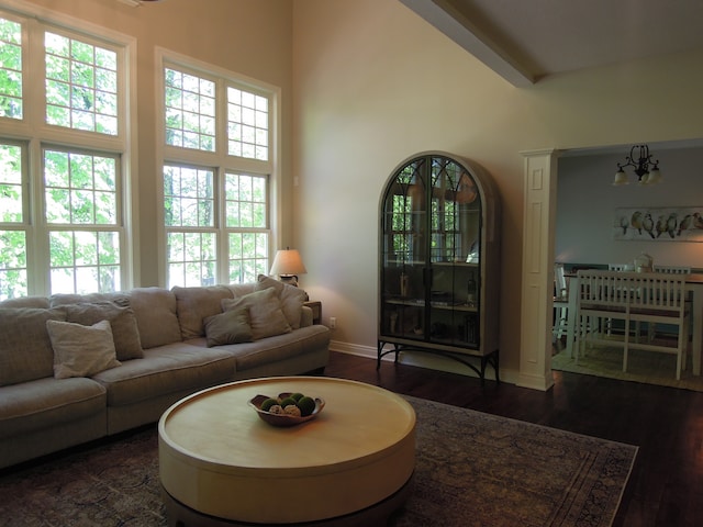 living room with plenty of natural light, dark wood-type flooring, beamed ceiling, and a high ceiling