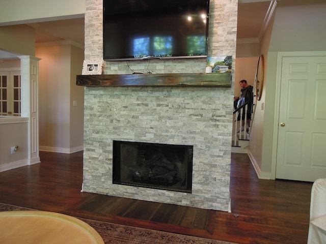 interior space featuring ornamental molding, dark hardwood / wood-style flooring, decorative columns, and a stone fireplace