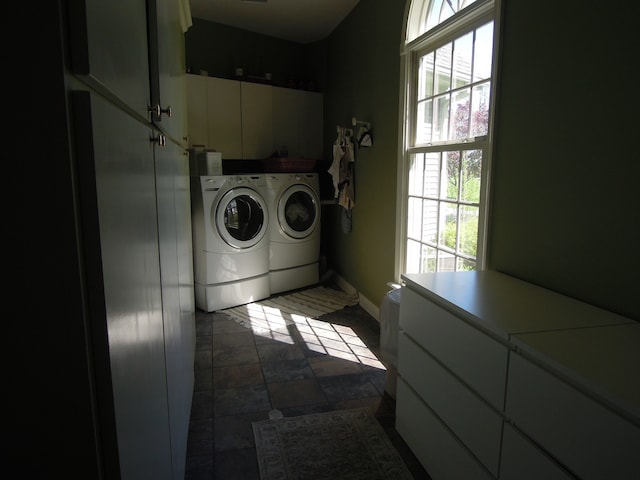 washroom with independent washer and dryer, dark tile floors, and cabinets