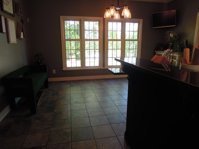 interior space with plenty of natural light, dark tile flooring, and a chandelier