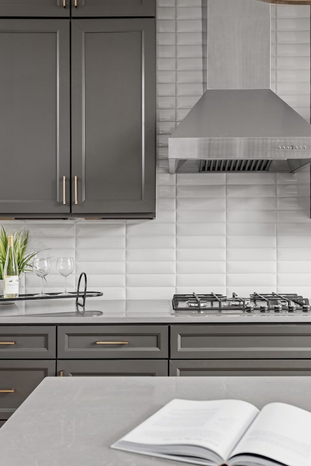 kitchen with wall chimney range hood, backsplash, and stainless steel gas stovetop