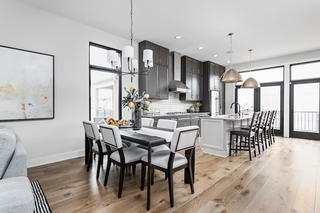 dining area featuring an inviting chandelier, sink, and light hardwood / wood-style floors