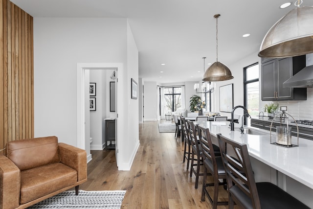 kitchen with a wealth of natural light, light hardwood / wood-style flooring, gray cabinets, and pendant lighting