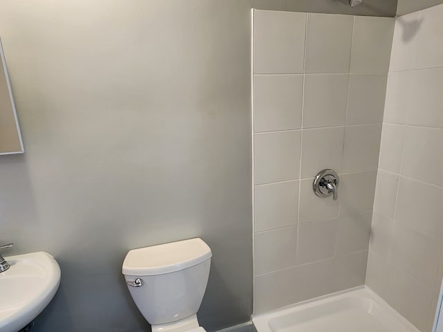 bathroom featuring sink, toilet, and a tile shower