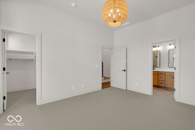 unfurnished bedroom with a chandelier, a walk in closet, light colored carpet, and a closet