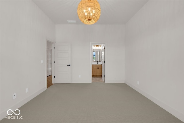 unfurnished bedroom featuring light carpet, a notable chandelier, and ensuite bath