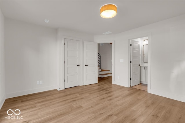 unfurnished bedroom featuring connected bathroom and light wood-type flooring