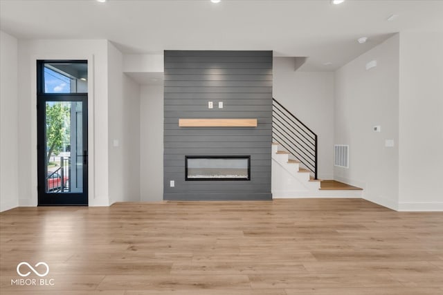 unfurnished living room featuring a large fireplace and light hardwood / wood-style floors