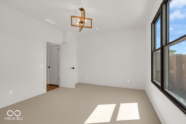 carpeted empty room featuring an inviting chandelier