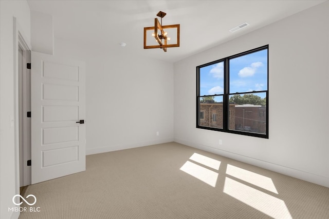 empty room featuring a notable chandelier and light colored carpet