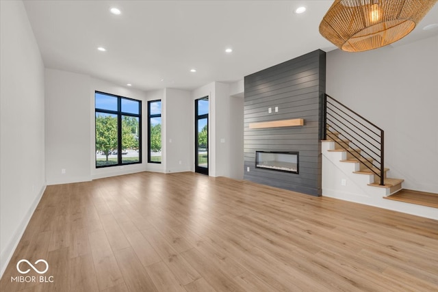 unfurnished living room with a fireplace, a chandelier, and light hardwood / wood-style floors